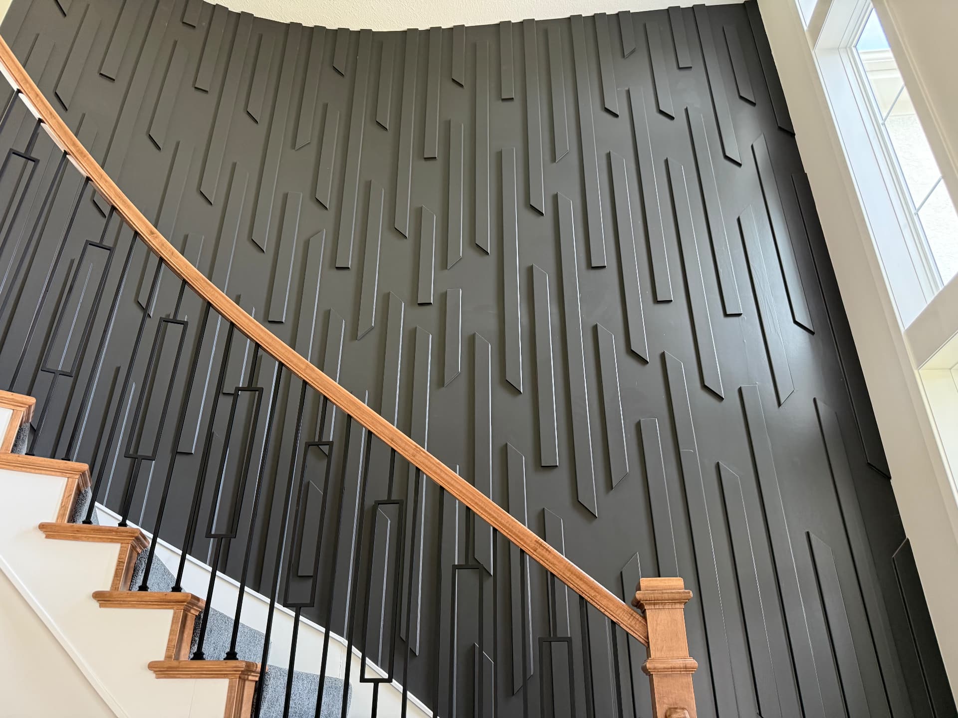 Custom black slat accent wall along a curved staircase in a Leawood, Kansas home remodel