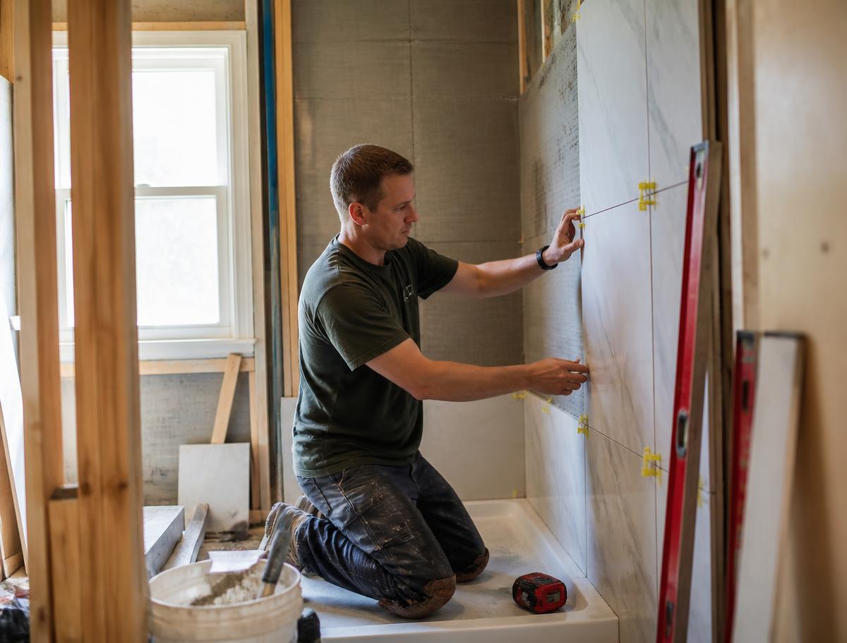 Revived Spaces tile setter installing large-format tile in a shower